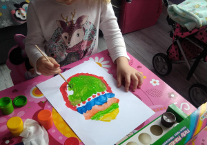 Dziewczynka maluje jajko farbami